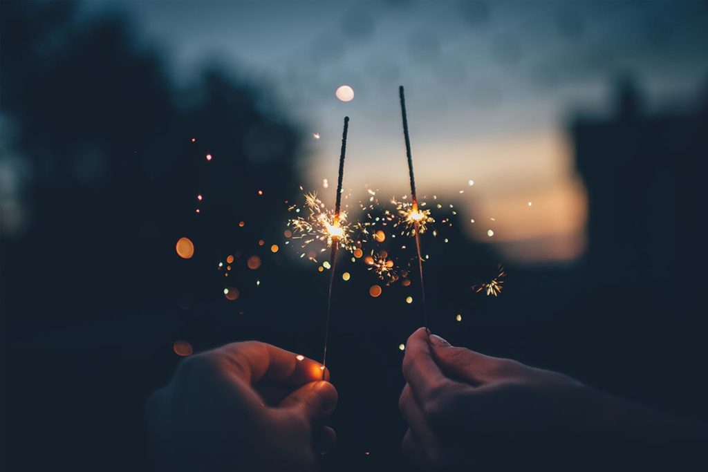 Two hands holding sparklers.